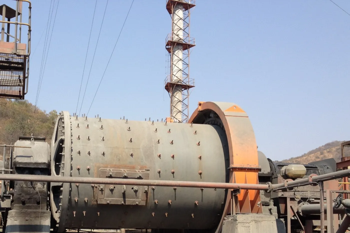A ball mill in front of a steel-framed stack at the processing plant