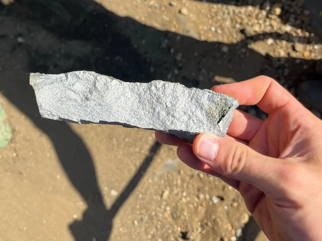 A piece of metallic material from the site held in the hand